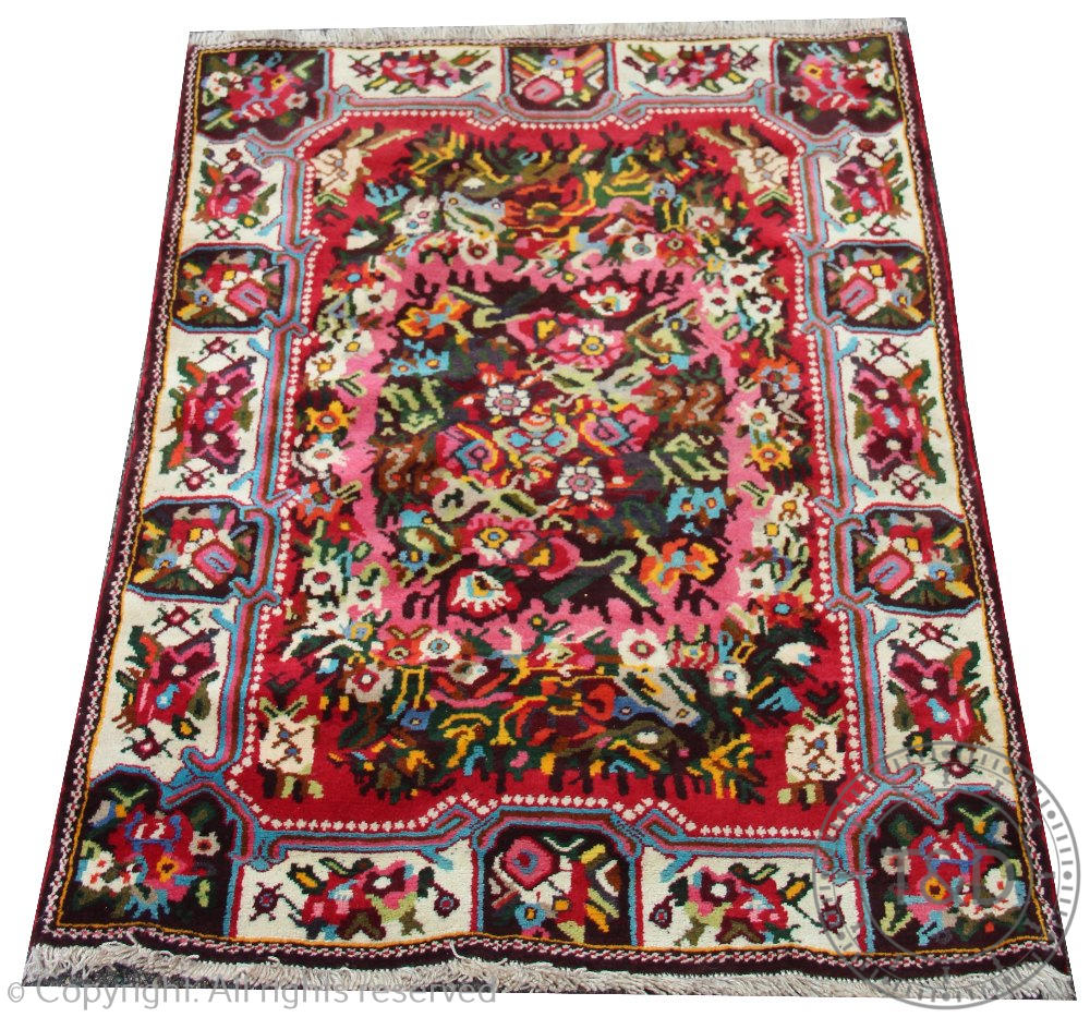 A Persian full pile wool rug, worked with a central floral spray,