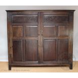 An 18th century style oak livery cupboard, with two panelled doors enclosing hanging rails,