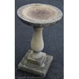 A reconstituted stone bird bath, the circular top on a baluster shaped column and on square base,