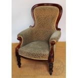 A Victorian carved mahogany salon chair, with scroll end arms, on turned legs,