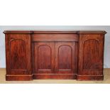 A Victorian mahogany inverted break front sideboard, with four panelled cupboard doors,