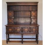 A 1920's Jacobean revival oak high back dresser, with two shelves and two fielded cupboard doors,