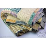 A quilted bed cover, worked with a checkered design in various pastel colours,