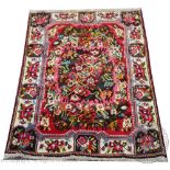 A Persian full pile wool rug, worked with a central floral spray,