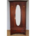 An Edwardian Art Nouveau wardrobe, with oval mirrored door and transfer Art Nouveau panels,