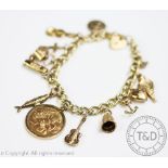 A 9ct yellow gold curb link bracelet hung with twelve assorted charms and an Edward VII gold