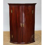 A George III mahogany bow front corner cabinet, with moulded cornice and brass 'H' hinges,