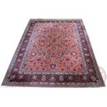 A Persian / Indian wool carpet, worked with an all over floral design against a pink ground,
