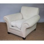 An early 20th century club type library chair, with cream upholstery, on bun feet,