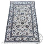 A Persian/Turkish hand woven wool rug worked with an all-over floral design against a cream ground,