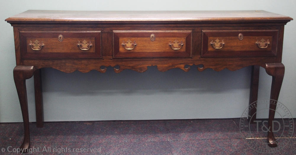 A George III style oak dresser, with three drawers above a shaped apron, on cabriole legs,