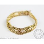 A yellow metal decorative bracelet, designed as eleven links surrounded by slender curb links,