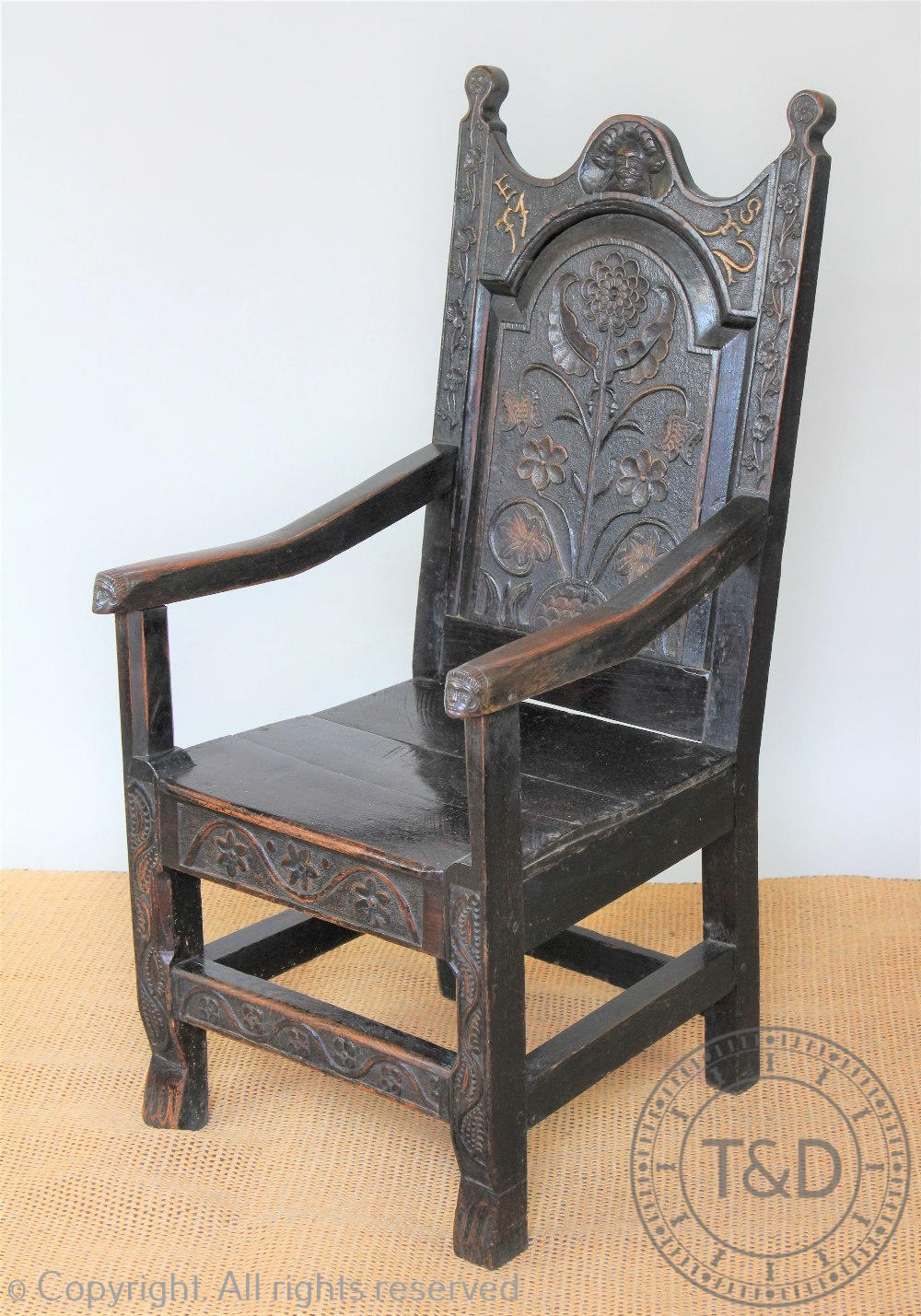 A 17th century style carved oak Wainscot type chair, the arched panelled back carved with flowers,