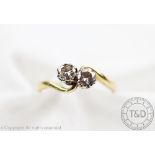 A two stone diamond cross-over ring, designed as two brilliant cut diamonds,