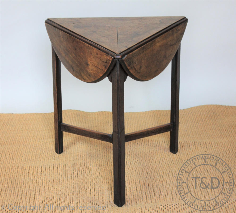 An early 19th century mahogany cricket type table, the rotating circular top with three leaves,