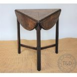 An early 19th century mahogany cricket type table, the rotating circular top with three leaves,