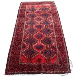 A Caucasian wool rug, worked with a geometric design against a red ground,