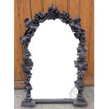 A late 19th century carved and stained wood mirror, of arched form with fruiting vine detailing,