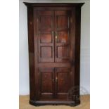 A George III oak corner cupboard, with moulded cornice above two pairs of panelled doors,