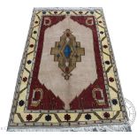 A Persian wool carpet, worked with a central geometric design against a pale ground,