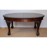 An early 20th century extending oval dining table, the top with a carved edge,