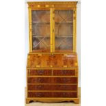 A George III style yew wood bureau bookcase, with two glazed doors above a fall,