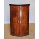 A George III oak bow front corner cabinet,