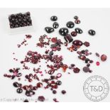 A collection of un-mounted garnets and red coloured stones, to include; faceted, cabochon,