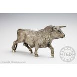 A white metal figure of a bull, the realistically designed bull modelled walking forward,