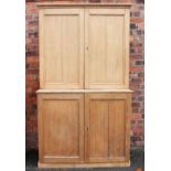 A Victorian style pine housekeepers cupboard, with four panelled doors, on plinth base,