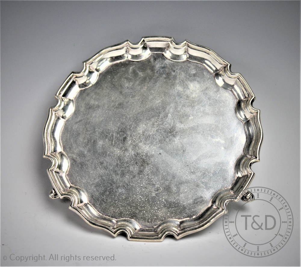 A George V silver salver, Adie Bros Ltd, the circular salver with pie crust rim on three hoof feet,