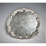 A George V silver salver, Adie Bros Ltd, the circular salver with pie crust rim on three hoof feet,