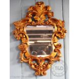 An 18th century style Florentine mirror, the elaborate scroll frame enclosing a mirror plate,