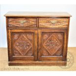 A late Victorian carved oak cabinet, with two drawers and two cupboard doors, on plinth base,