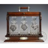 A late Victorian oak tantalus enclosing three decanters and stoppers,