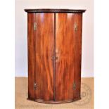 A George III mahogany bow front hanging corner cabinet,