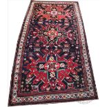A Caucasian wool carpet, worked with geometric foliate panels against a blue ground,
