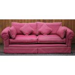 A three seater sofa in claret upholstery and scatter cushions,