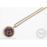 An amethyst set yellow metal pendant, of stylised floral design, with attached yellow metal chain,