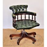 A stained wood office swivel desk chair, with button back green leather upholstery,
