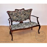 An Edwardian carved mahogany salon settee, of serpentine form, with floral upholstery,