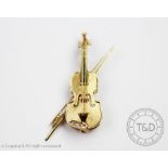 A brooch/pendant in the form of a violin and bow,