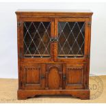 An oak Old Charm type bookcase, with two glazed doors and two cupboard doors, on bracket feet,