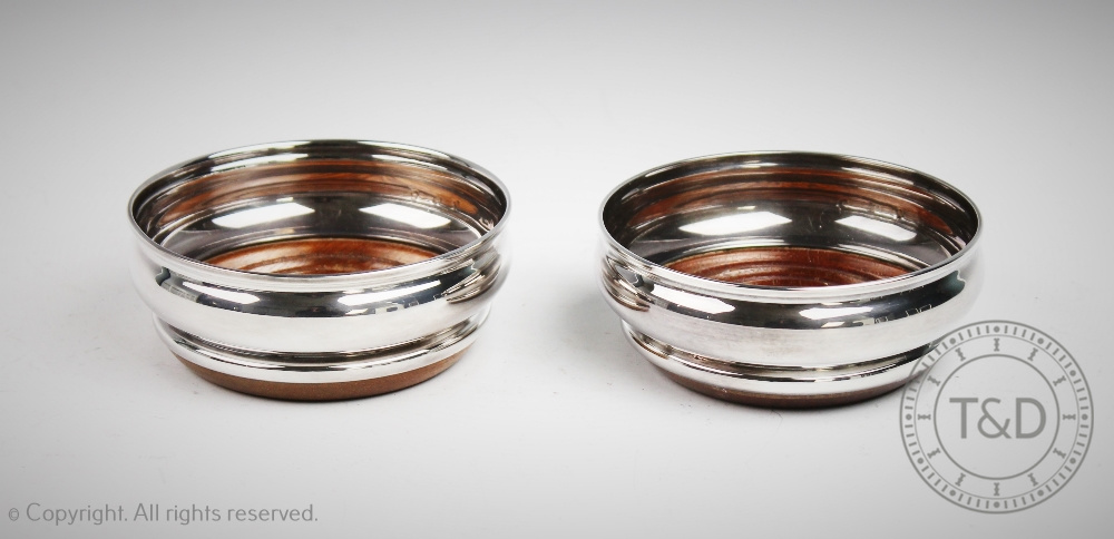 A pair of silver bottle coasters, Birmingham 1975, of plain polished form, with turned wooden bases,