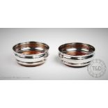 A pair of silver bottle coasters, Birmingham 1975, of plain polished form, with turned wooden bases,