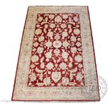 A modern machine made carpet, worked with pale flowers against a red ground,