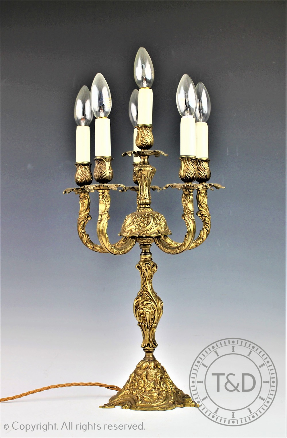 A Rococo style cast bronzed candelabra, modelled on a scroll base supporting five branches,