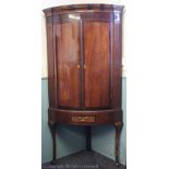 A George III inlaid oak bow front corner cabinet on later stand, of large proportions,