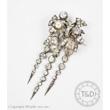 A Victorian paste set brooch, designed as a stylised floral section suspending three tapering drops,