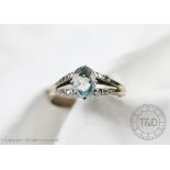 An aquamarine and diamond ring, the central oval aquamarine within bifurcated,